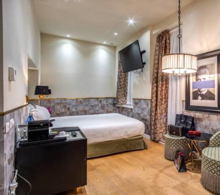 Elegant hotel room with bed, chairs, and TV.