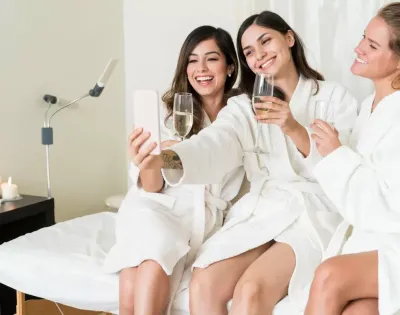 Tre donne in accappatoio brindano e scattano un selfie.