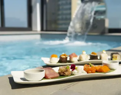 Sushi servito a bordo piscina con cascata sullo sfondo.