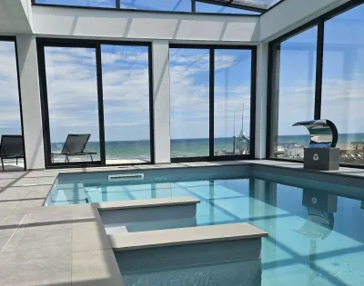 Piscina interna con vista mare e ampie finestre.