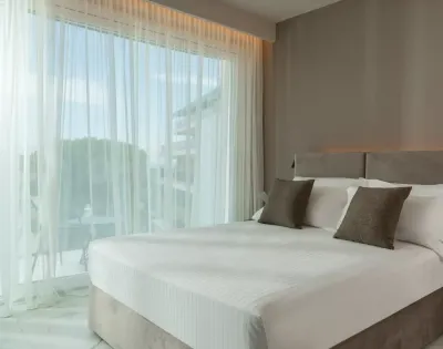Camera moderna con letto matrimoniale e tende trasparenti.