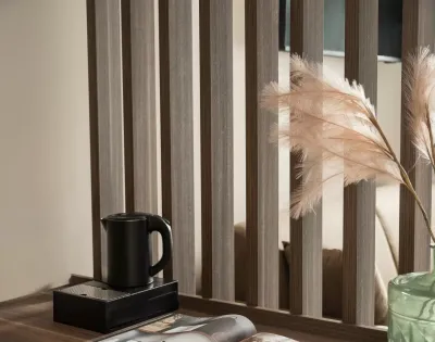 Scrivania con libro aperto, brocca nera e vaso verde decorativo.