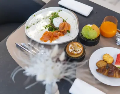 Colazione gourmet con salmone, avocado, dolci e succo d'arancia.