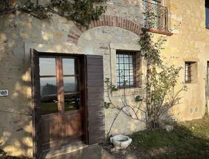 Porta in legno su casa in pietra con rampicante.