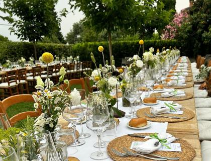 Tavola all'aperto elegante con fiori, piatti e bicchieri.