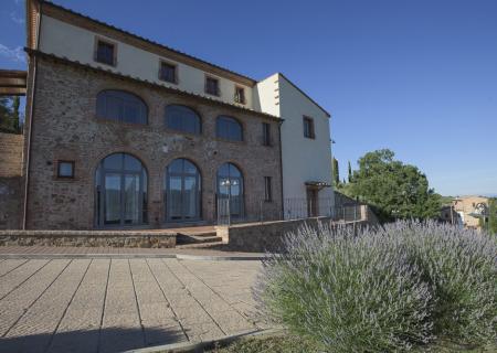 Edificio rustico in pietra con lavanda in primo piano.