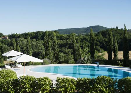 Piscina panoramica con vista su colline verdi e cipressi.