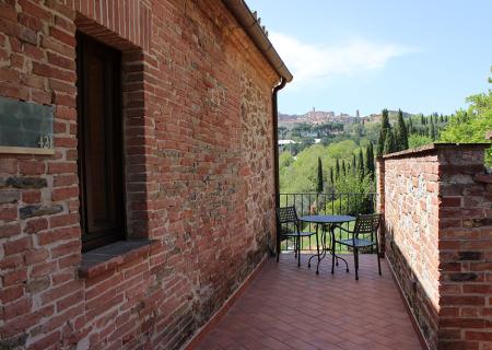 Terrazza rustica con vista panoramica su colline verdi e città lontana.