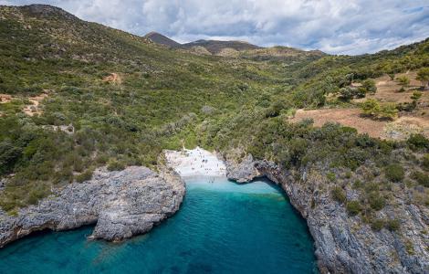 Spiaggia nascosta tra scogli e natura, mare turchese, atmosfera serena.