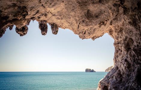 Vista mozzafiato da una grotta verso il mare blu e l'orizzonte sereno.