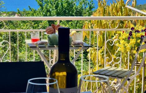 Vista mare con tavolo apparecchiato, vino e fiori. Atmosfera rilassante e serena.