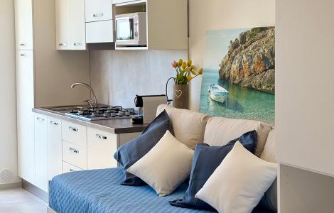 Elegante monolocale con cucina moderna, divano blu e decorazioni rilassanti.