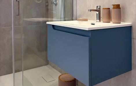 Bagno moderno, elegante e luminoso con doccia in vetro e mobile blu.