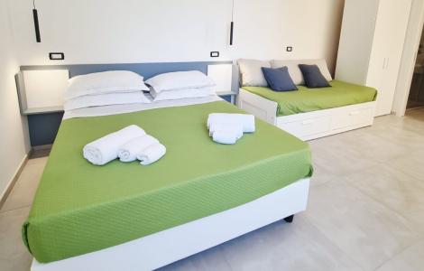 Camera luminosa con letto verde e asciugamani, atmosfera fresca e accogliente.