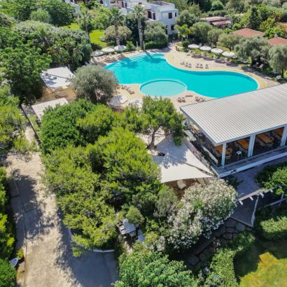 Vista aerea di un resort lussureggiante con piscina, immerso nella natura.