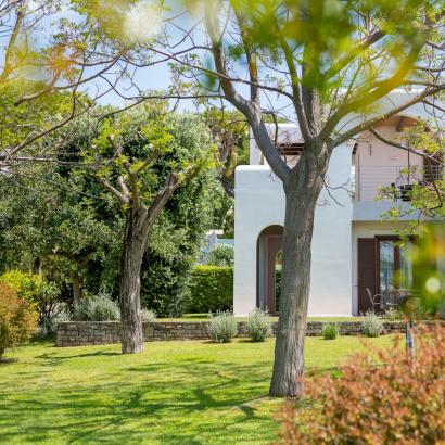 Giardino sereno con alberi e casa bianca, atmosfera di pace e tranquillità.