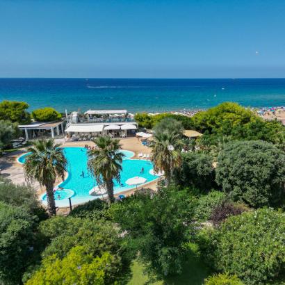 Piscina tropicale e spiaggia paradisiaca con mare blu, sole e relax.