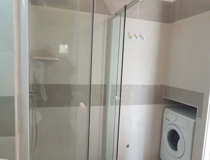 Bagno moderno con doccia elegante e lavatrice, atmosfera pulita e ordinata.