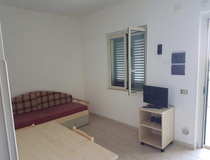 Stanza luminosa con divano e TV, atmosfera semplice e accogliente.