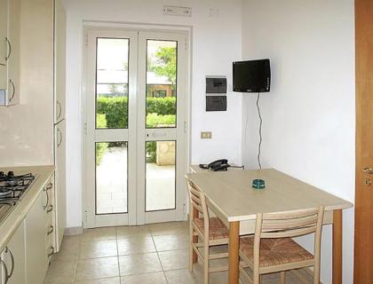 Cucina luminosa con tavolo, sedie e vista sul giardino verde.