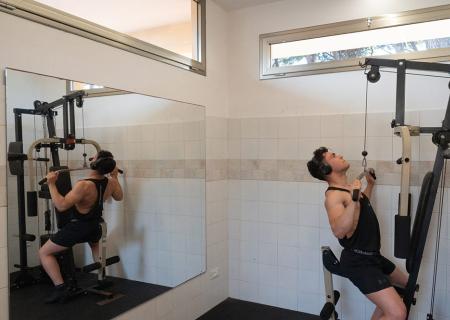 Uomo concentrato in palestra, solleva pesi con determinazione.