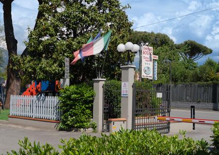 Ingresso di un campeggio con bandiera italiana e giochi colorati.