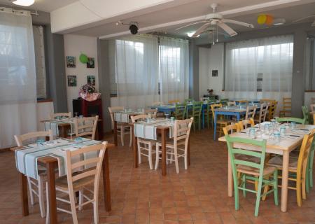 Ristorante accogliente con tavoli colorati, atmosfera luminosa e festosa.