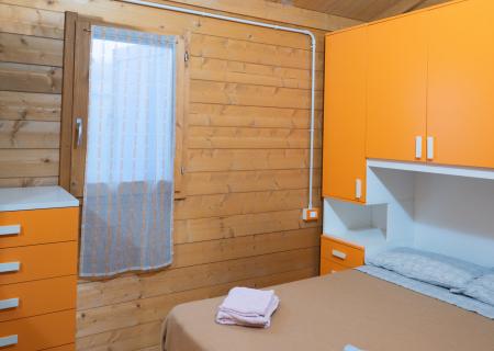 Cozy wooden room with orange furniture and a tidy bed.