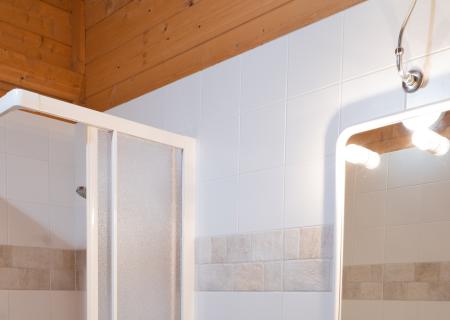Cozy bathroom with shower, sink, and bidet, warmly lit.