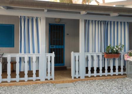 Cozy porch with blue striped curtains and colorful flowers.