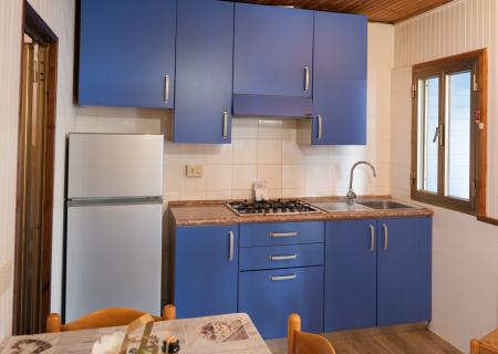 Cozy kitchen with blue cabinets, silver fridge, and bright window.