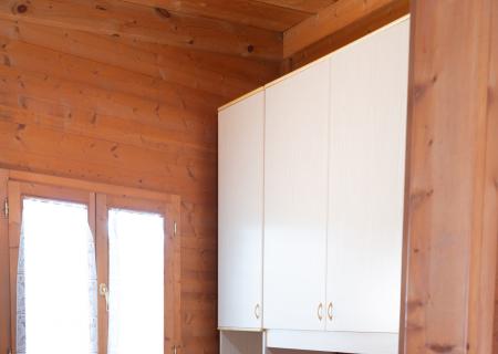 Cozy wooden room, bed with blue sheets, warm and relaxing atmosphere.