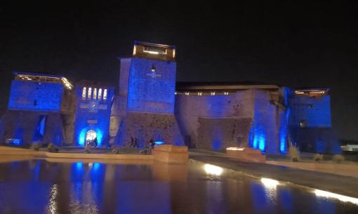 Castello illuminato di notte con riflessi blu sull'acqua.