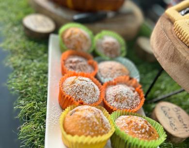 Bunte, süße Muffins mit Puderzucker auf einem grünen Tablett.