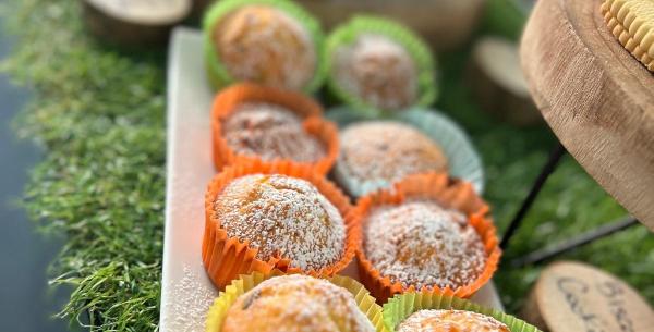 Bunte, süße Muffins mit Puderzucker auf einem grünen Tablett.