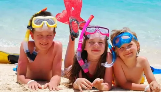 Bambini sorridenti con maschere da snorkeling sulla spiaggia.