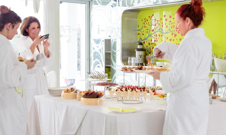 Personen in Bademänteln genießen ein Buffet in modernem Ambiente.