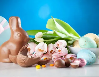 Chocolate bunny, colorful eggs, and tulips on a blue background.