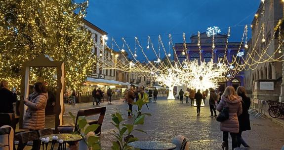 Strada decorata con luci natalizie e grande albero illuminato.