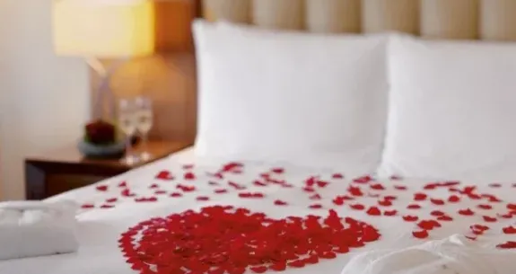 Letto con petali di rosa a forma di cuore, atmosfera romantica.