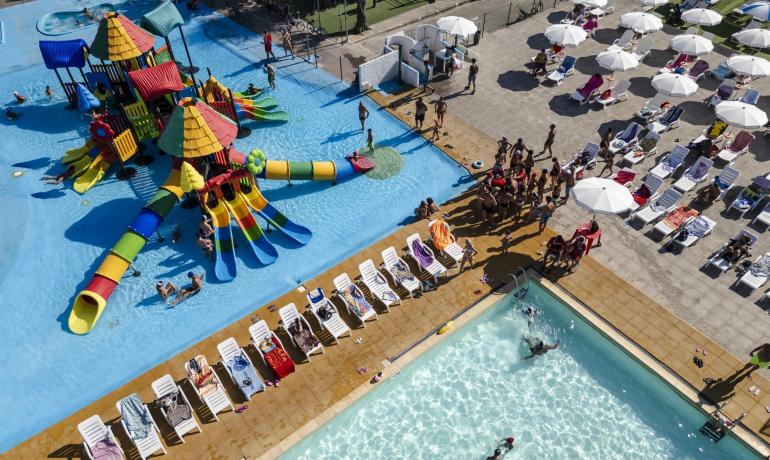 Parco acquatico con scivoli colorati e piscina affollata.