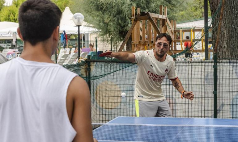 Deux personnes jouent au ping-pong en plein air dans un parc.