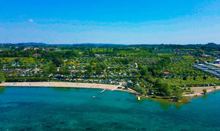 Panoramablick auf einen Strand und Campingplatz im Grünen.