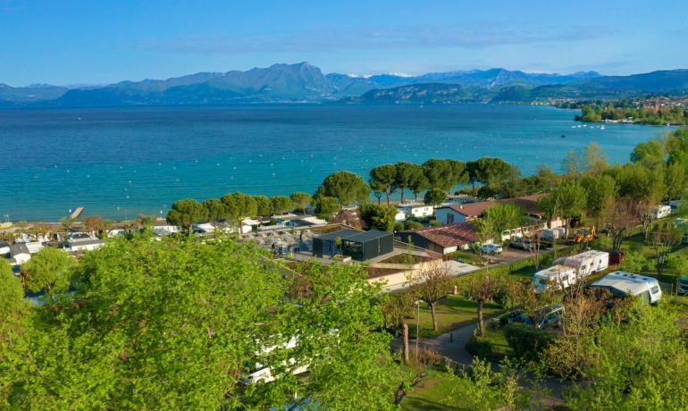 Malerischer Campingplatz am See mit Bergen im Hintergrund.