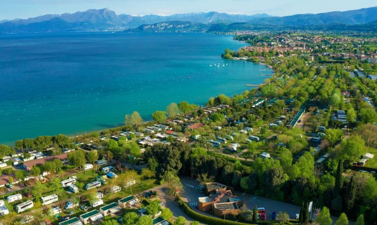 Luftaufnahme eines Campingplatzes am See, umgeben von Natur.