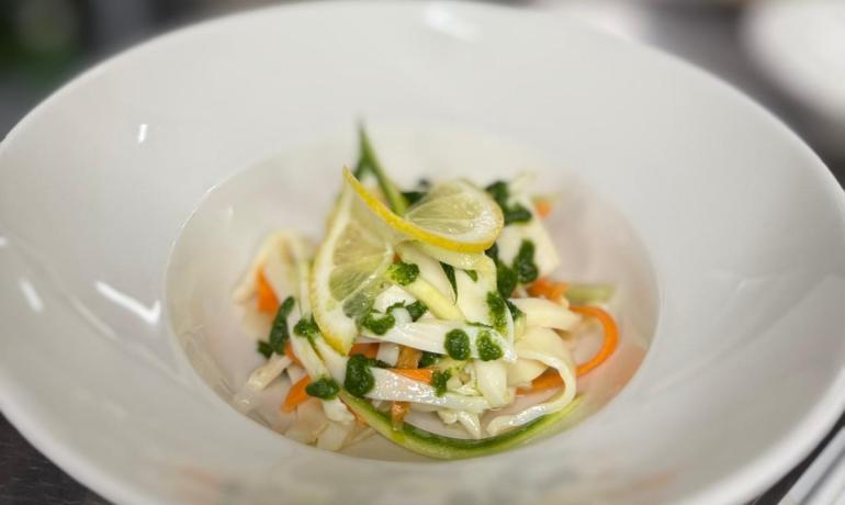Piatto di pasta fresca con verdure colorate e fette di limone.