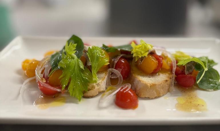 Crostini colorati con pomodori e verdure fresche su piatto bianco.
