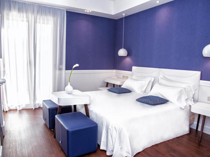 Chambre moderne avec murs bleus et meubles blancs.