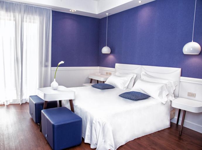 Chambre moderne avec murs bleus, lit blanc et décoration minimaliste.