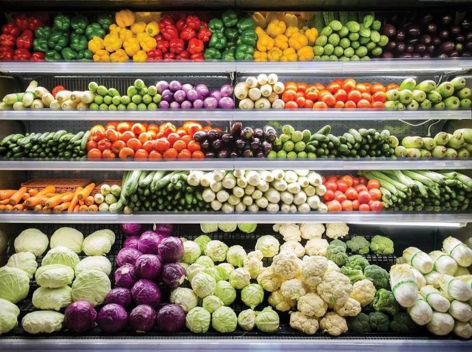 Exposition colorée de légumes frais dans un supermarché.